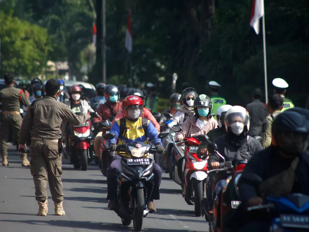 Petugas memantau pengendara sepeda motor dan mobil yang melanggar kepatuhan penggunaan masker untuk kemudia dites usap OVID-19 saat razia di Solo, Jawa Tengah, Jumat (18/6/2021). (ANTARA/Maulana Surya)