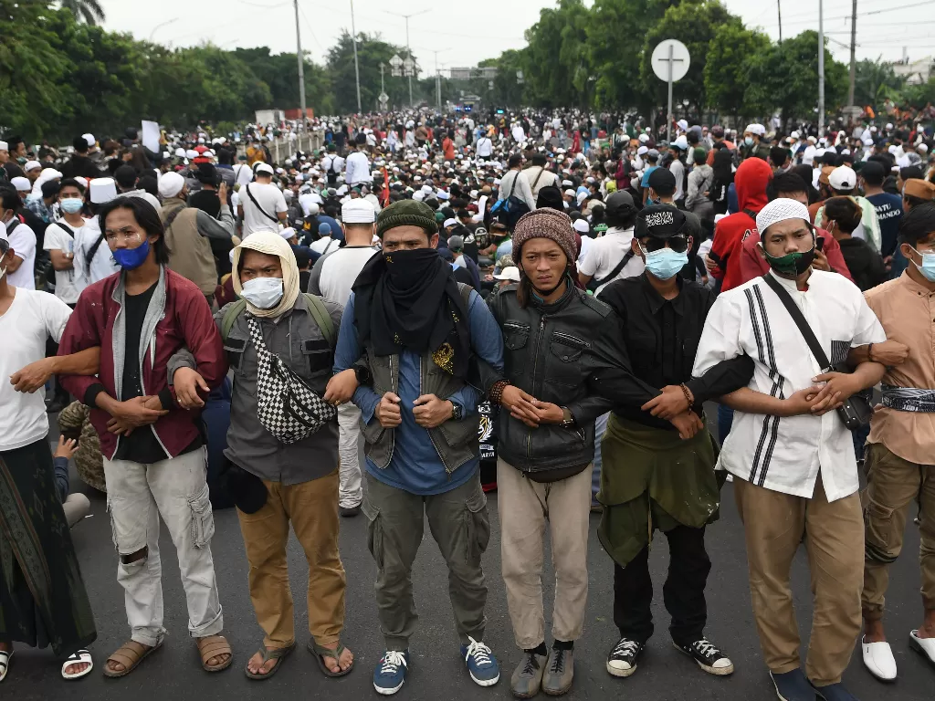 Massa pendukung Rizieq Shihab bergandengan tangan membentuk barikade di kawasan I Gusti Ngurah Rai saat akan menuju Pengadilan Negeri (PN) Jakarta Timur, Kamis (24/6/2021). (photo/ANTARA FOTO/M Risyal Hidayat)