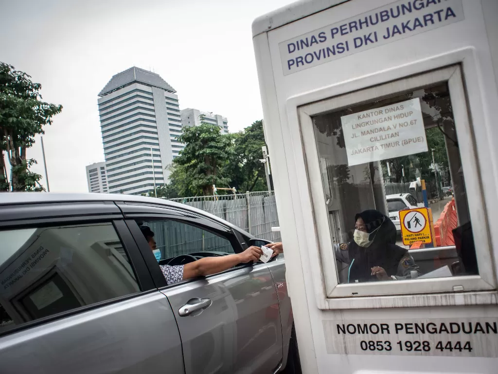 Pengendara mobil menyerahkan karcis parkir ke petugas di lapangan IRTI Monas, Jakarta Pusat, Jakarta, Rabu (23/6/2021). (photo/ANTARA FOTO/Aprillio Akbar/ilustrasi)