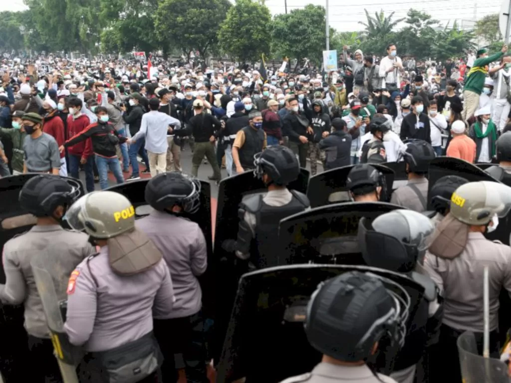 Polisi memblokade massa pendukung Rizieq Shihab di kawasan I Gusti Ngurah Rai saat akan menuju Pengadilan Negeri (PN) Jakarta Timur, Kamis (24/6/2021). (ANTARA FOTO/M Risyal Hidayat)