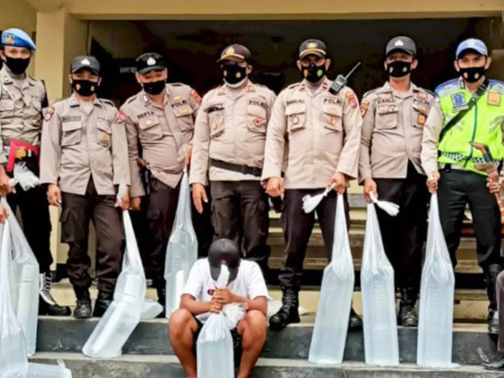 Sejumlah anggota kepolisian menunjukkan minuman keras yang dimasukkan ke dalam plastik di Kupang. (photo/ANTARA/HO-Humas Polda NTT)