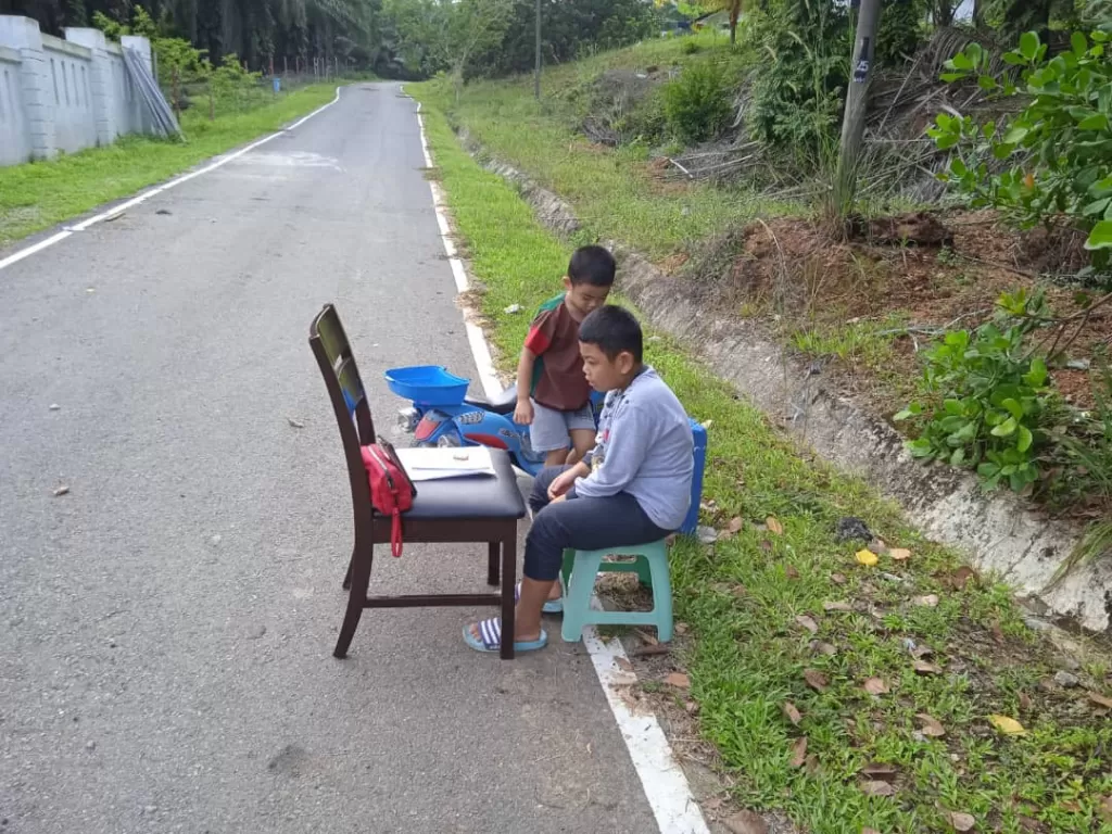 Duduk di pinggir jalan untuk dapatkan koneksi internet agar bisa belajar. (Twitter/@AimanPaku)