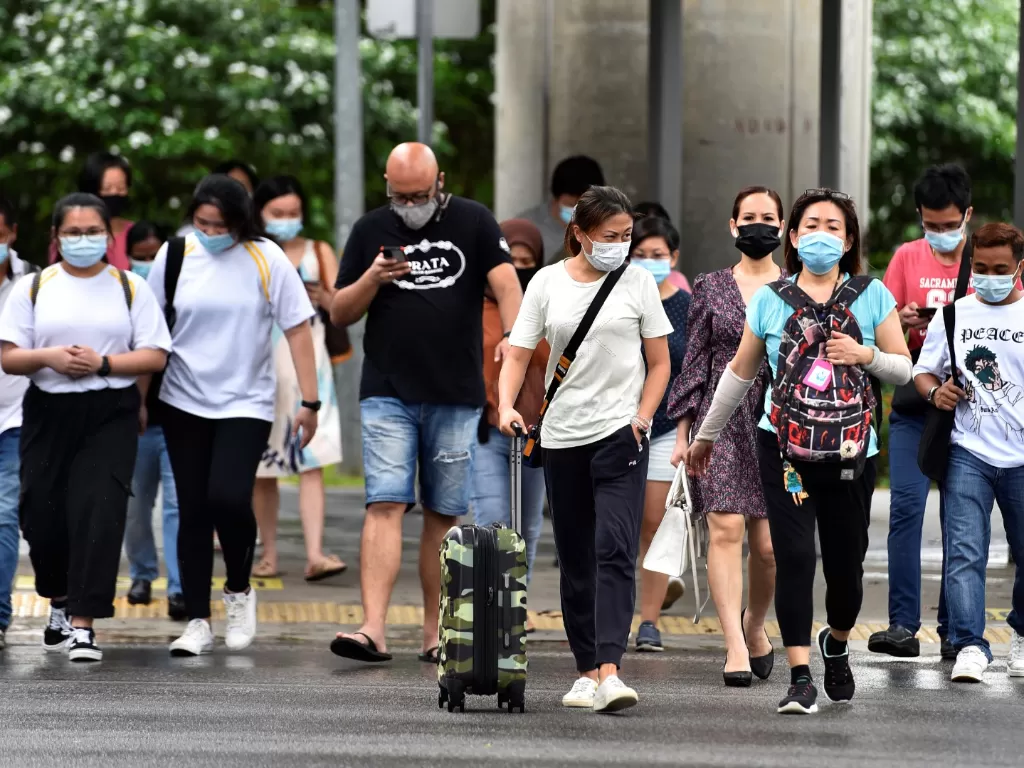 Warga memakai masker pelindung menyebrang jalan di tengah penyebaran penyakit virus korona (COVID-19) di Singapura. (ANTARA FOTO/REUTERS/Caroline Chia)
