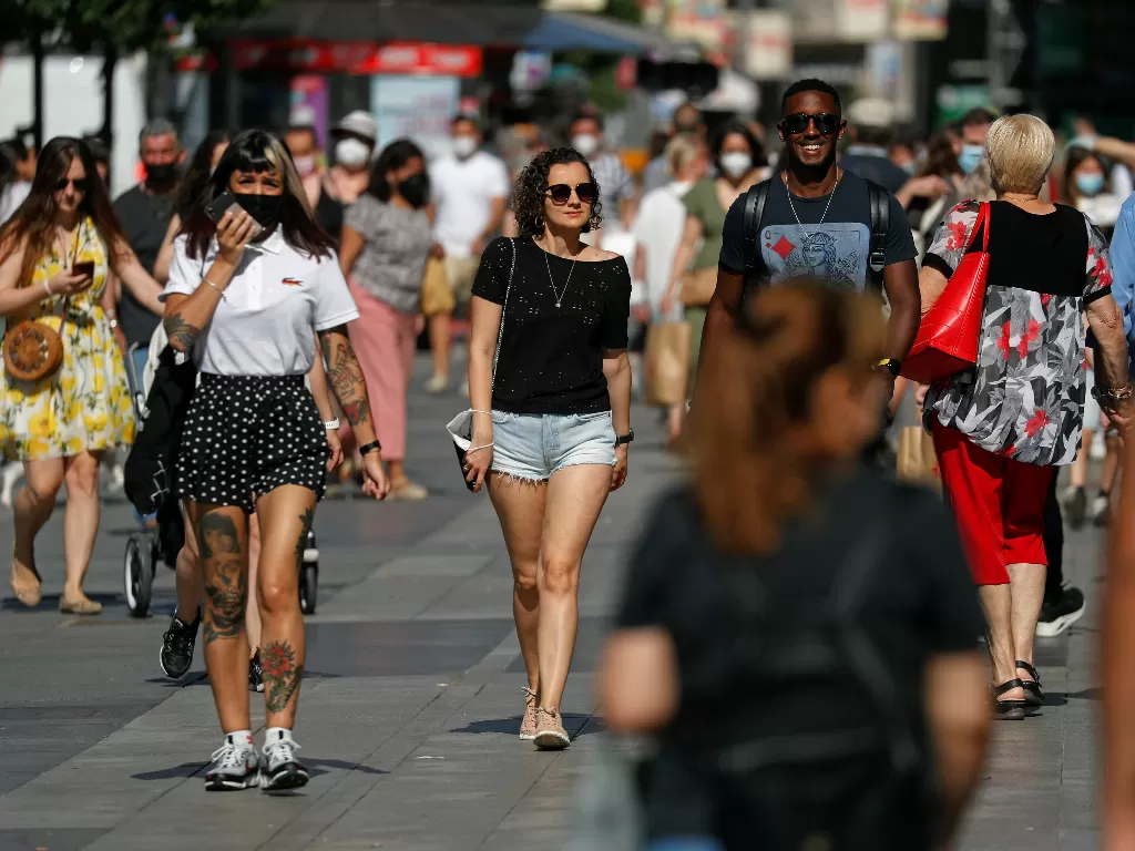 Orang-orang, beberapa tanpa masker pelindung, berjalan di pusat kota Madrid, karena masker tidak lagi diperlukan di luar ruangan mulai 26 Juni, di tengah pandemi penyakit coronavirus (COVID-19), Spanyol, 26 Juni 2021. (photo/REUTERS/Susana Vera_