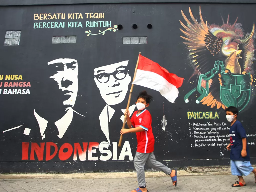 Dua bocah berlari mengibarkan bendera merah putih saat perayaan hari lahir Pancasila di Kampung Tematik Kampung Teras Pancasila, Karang Tengah, Tangerang, Banten, Selasa (1/6/2021). (ANTARA/Muhammad Iqbal)