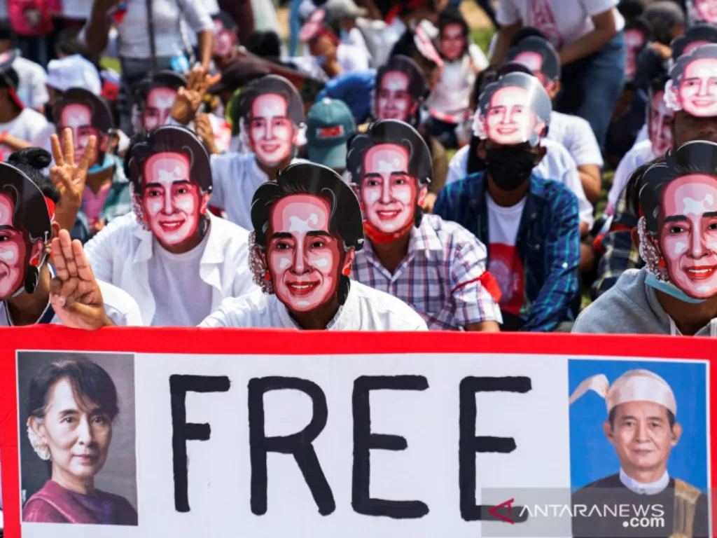Pengunjuk rasa memakai topeng mirip pemimpin yang digulingkan Aung San Suu Kyi, memperlihatkan salam tiga jari saat mereka berpartisipasi dalam sebuah protes terhadap kup militer di Yangon, Myanmar, Minggu (28/2/2021). (REUTERS/Stringer).