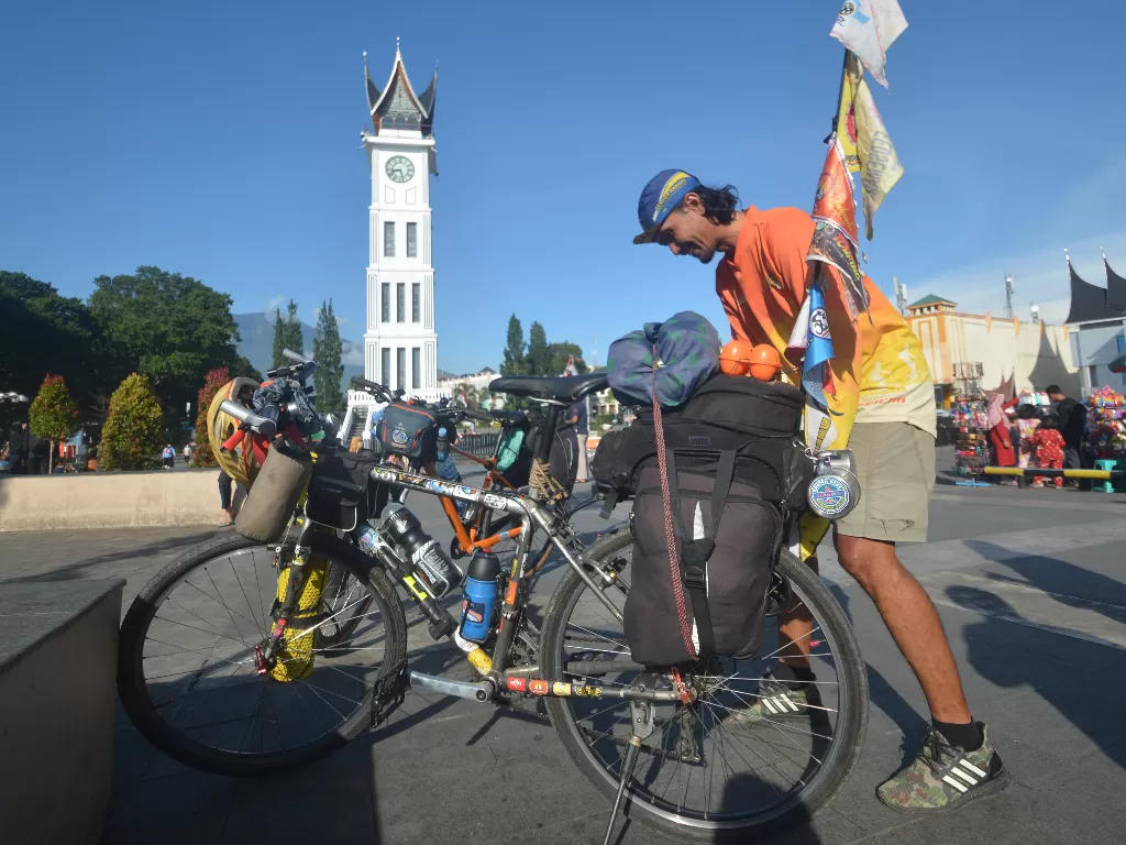 Pesepeda Haris Sutansyah mengecek kondisi sepedanya saat berhenti di kawasan Jam Gadang (ANTARA FOTO/Iggoy el Fitra)