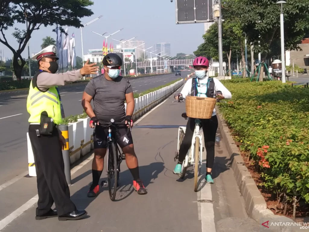 Polisi memberhentikan pesepeda di jalur sepeda permanen di Jalan Sudirman, Jakarta, pada hari pertama PPKM Darurat (ANTARA/Dewa Ketut Sudiarta Wiguna)