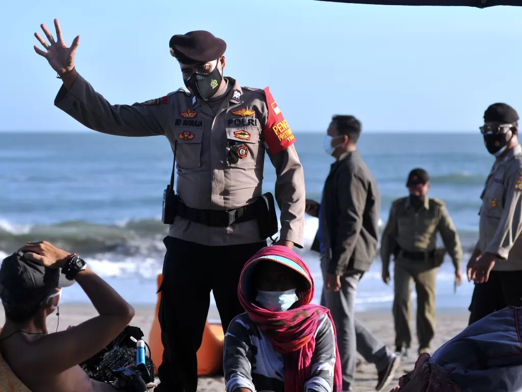 Petugas Satpol PP dan Polisi meminta wisatawan untuk meninggalkan objek wisata pantai (ANTARA FOTO/Fikri Yusuf)