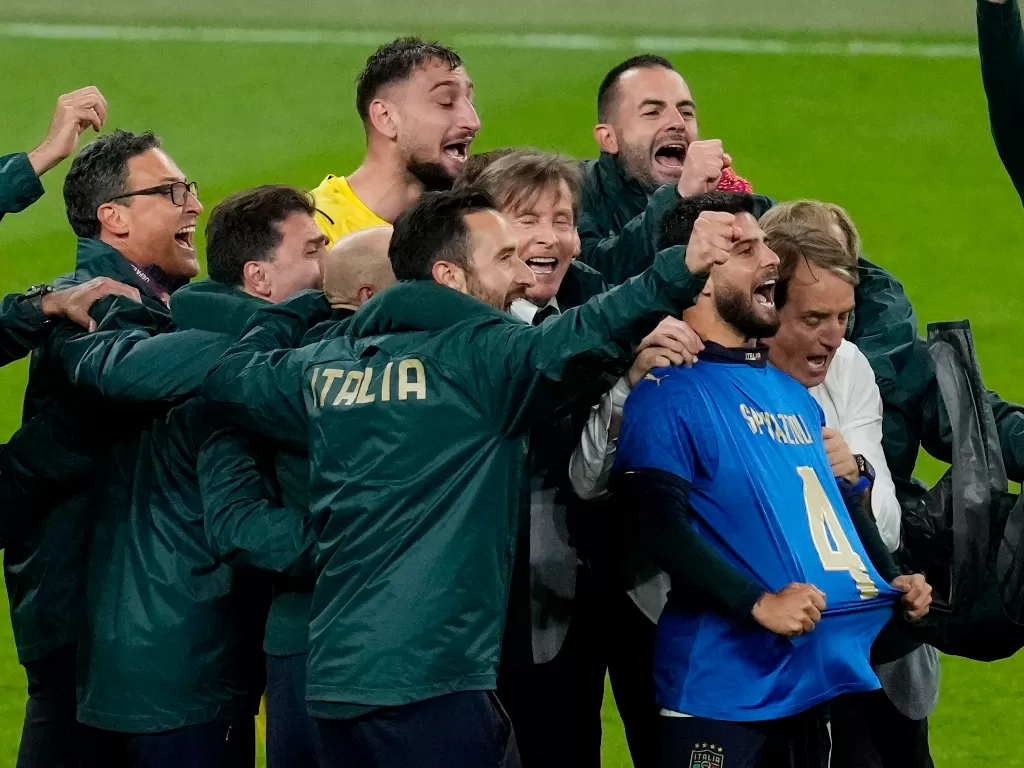 Penyerang Italia Lorenzo Insigne, bersama pelatih Roberto Mancini dan juga staf serta rekan setim merayakannya dengan kaus bertuliskan nama Leonardo Spinazzola usai memenangkan adu penalti. (REUTERS/Matt Dunham)