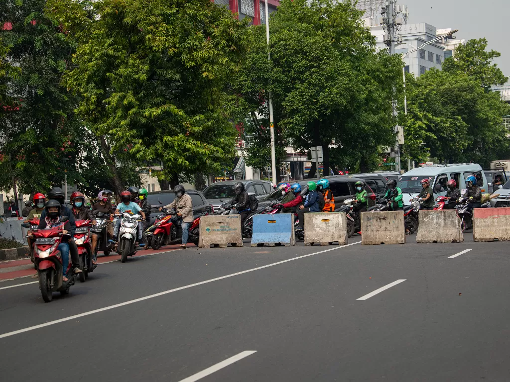 Sejumlah kendaraan bermotor menerobos bagian jalan yang tidak tertutup beton di posko penyekatan tanpa penjagaan petugas di Jalan Salemba Raya, Jakarta Pusat. (ANTARA FOTO/Aditya Pradana Putra).
