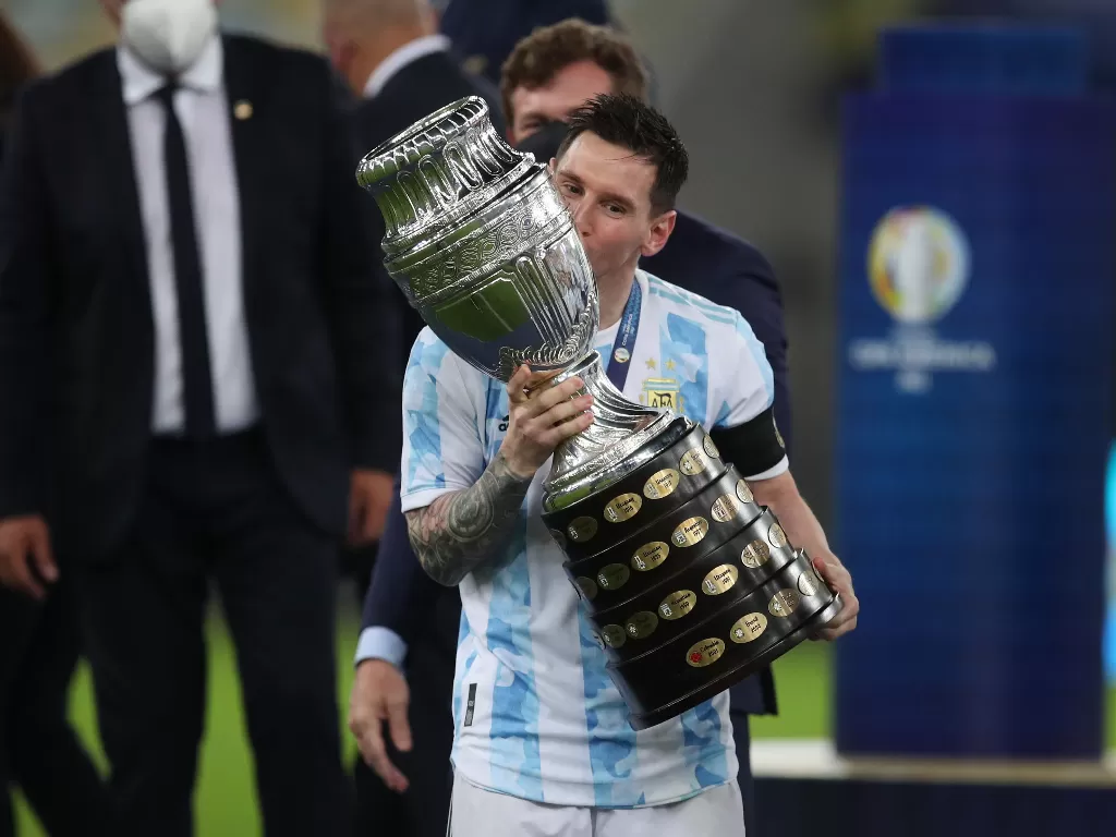 Lionel Messi cium trofi Copa America 2021. (photo/REUTERS/RICARDO MORAES)