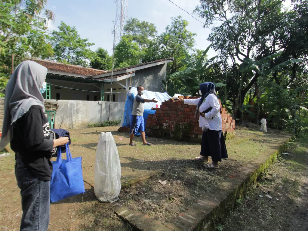 Pengurus RT memberikan masker kepada salah satu warga terkonfirmasi positif COVID-19 saat menjalani isolasi mandiri di desa Lohbener, Indramayu, Jawa Barat, Rabu (30/6/2021). (ANTARA/Dedhez Anggara)