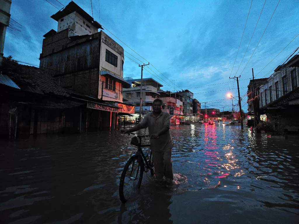Warga menuntun sepeda saat menerobos banjir (ANTARA FOTO/Wahdi Septiawan)