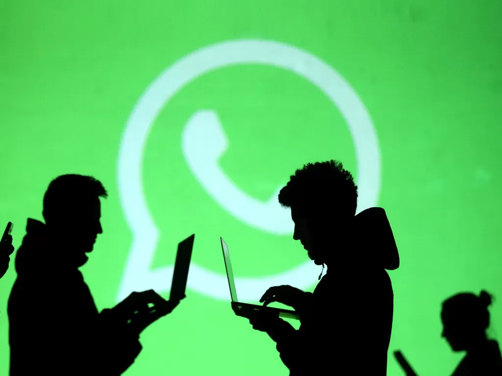 Ilustrasi beberapa orang menggunakan laptop di depan logo WhatsApp (photo/REUTERS/Dado Ruvic)