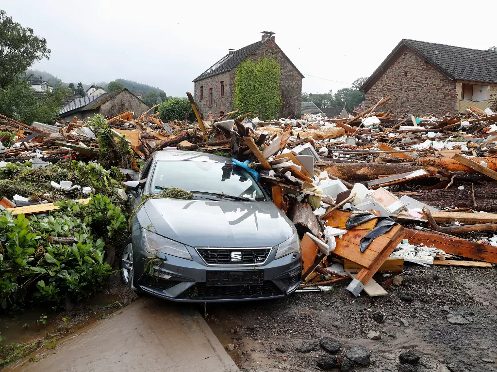 Sebuah mobil sebagian tertutup puing-puing dari rumah yang runtuh (REUTERS/Wolfgang Rattay)