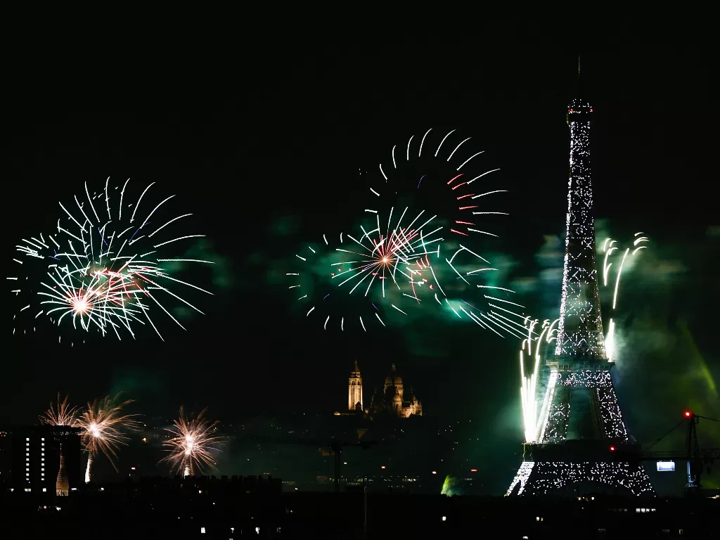 Kembang api meledak di sekitar Menara Eiffel selama perayaan untuk memperingati Hari Bastille, di Paris, Prancis, 14 Juli 2021. (photo/REUTERS/Christian Hartmann)