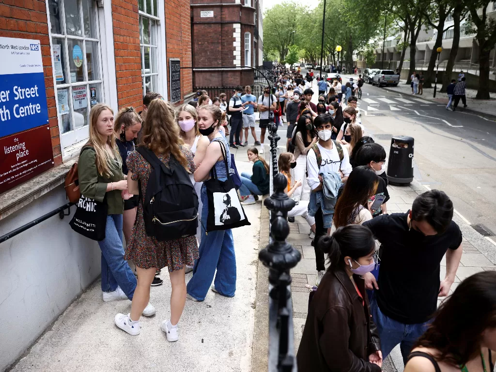 Orang-orang mengantri di luar pusat vaksinasi untuk kaum muda dan pelajar di Hunter Street Health Centre, di tengah wabah penyakit virus corona (COVID-19), di London. (REUTERS/Henry Nicholls)