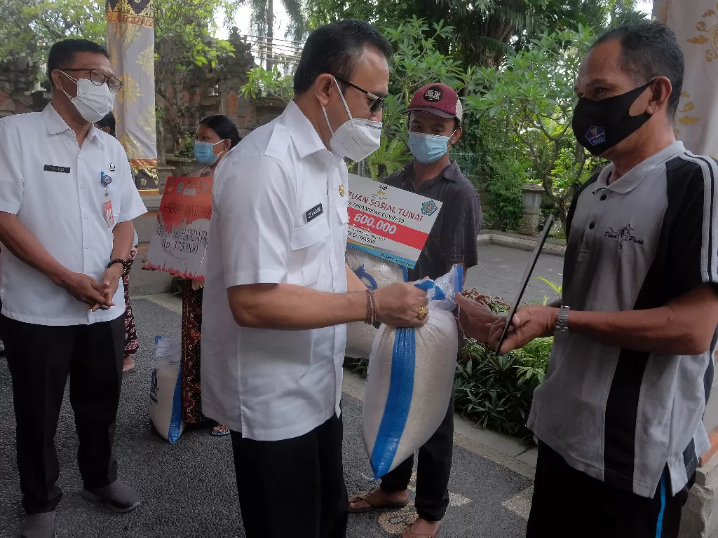 Wali Kota Denpasar I Gusti Ngurah Jaya Negara (tengah) menyerahkan bantuan kepada warga secara simbolis (ANTARA FOTO/Nyoman Hendra Wibowo)