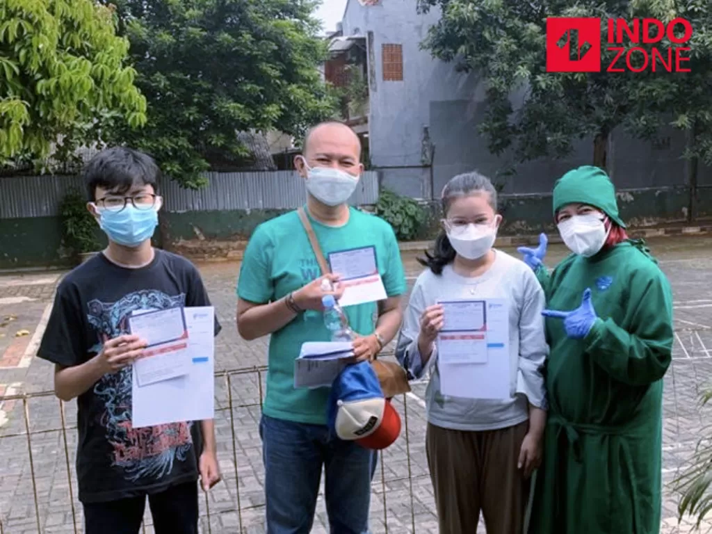 Warga menunjukan kartu vaksin usai mengikuti vaksinasi di salah satu puskesmas di Jakarta Timur. (INDOZONE/Fahmy Fotaleno)