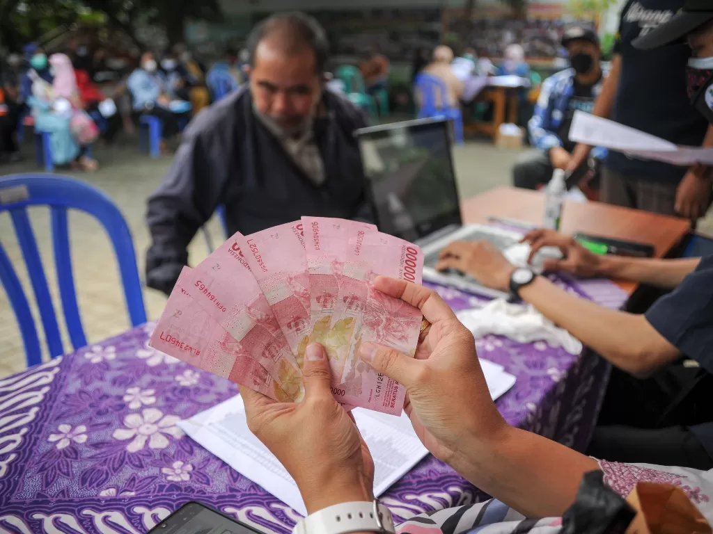 Petugas menunjukan uang tunai saat pembagian bantuan sosial tunai di Jajaway, Antapani Kidul, Bandung, Jawa Barat. (ANTARA/Raisan Al Farisi)