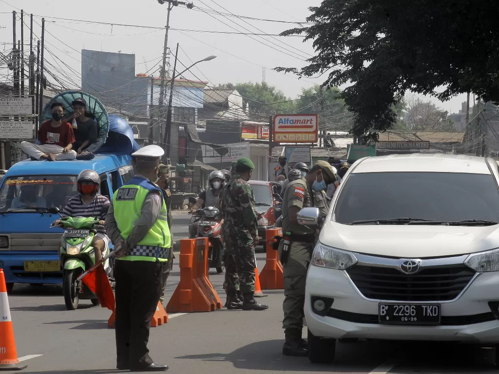 Petugas gabungan Satgas Covid-19 Kabupaten Bogor melakukan penyekatan kendaraan di perbatasan Bogor-Depok, Cibinong, Kabupaten Bogor, Jawa Barat, Minggu (25/7/2021). (ANTARA FOTO/Yulius Satria Wijaya)