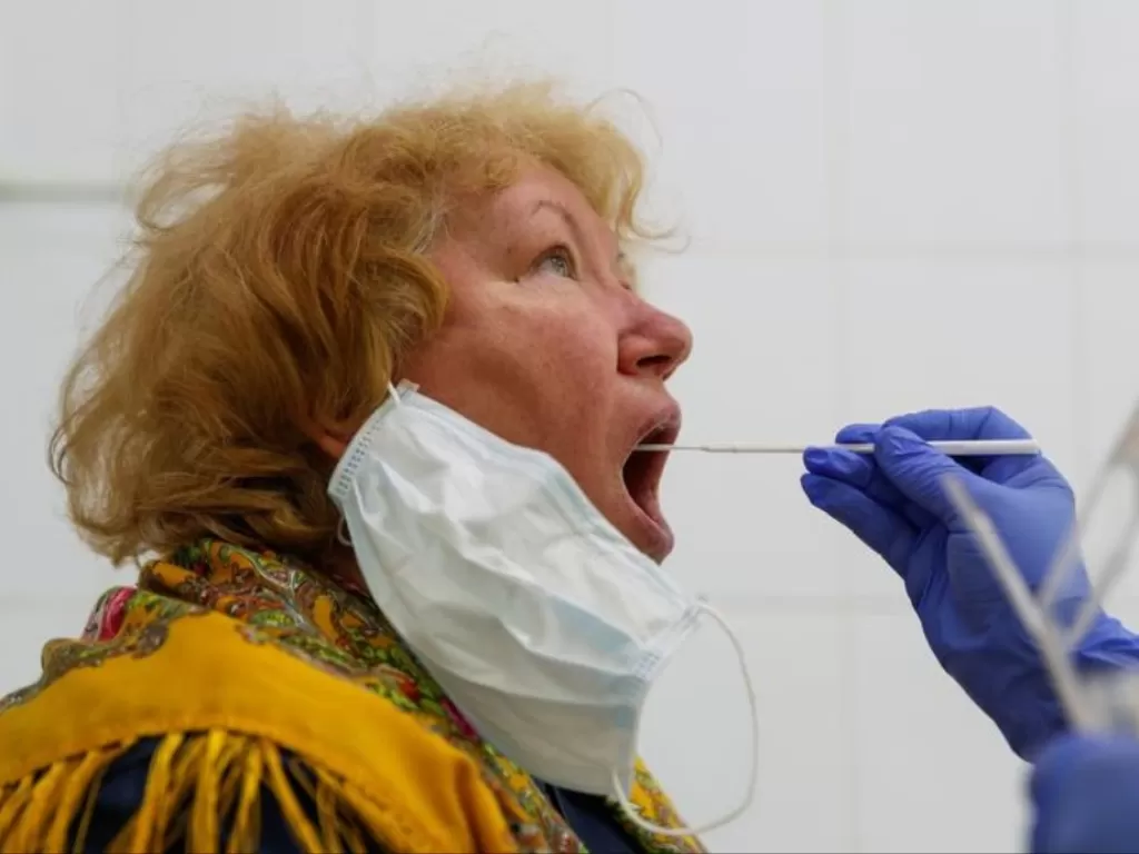Petugas kesehatan melakukan tes swab pada seorang perempuan di Moskow, Rusia, Jumat (15/5/2020). (REUTERS/Maxim Shemetov)