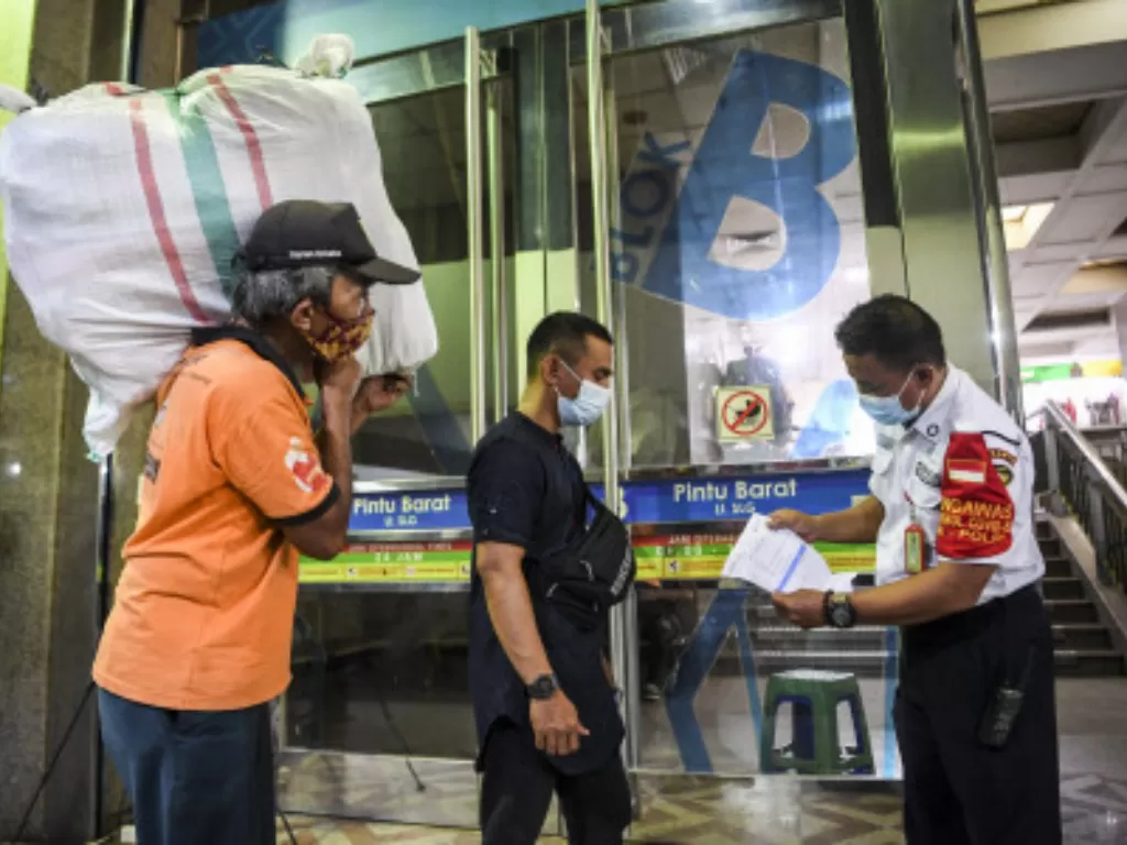 Petugas memeriksa kartu vaksinasi seorang pedagang yang akan memasuki Blok B Pasar Tanah Abang, Jakarta, Senin (26/7/2021). (ANTARA FOTO/Hafidz Mubarak A)