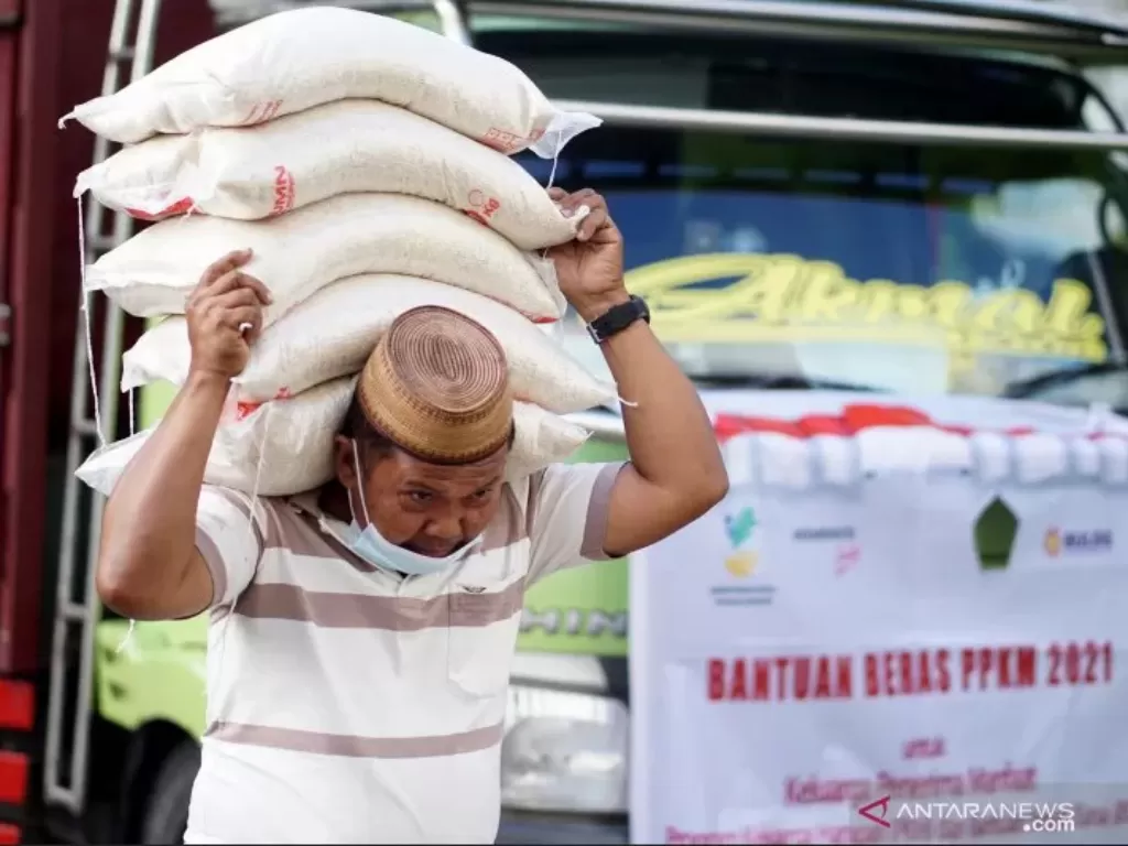 Seorang pekerja memanggul beras bantuan sosial di halaman kantor Bupati Bone Bolango, Kabupaten Bone Bolango, Gorontalo (ANTARA/Adiwinata Solihin)