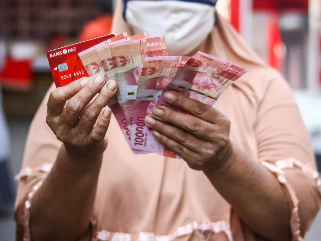  Ilustrasi. Warga menunjukkan uang bantuan sosial tunai atau BST usai mengambil di ATM Bank DKI, Jakarta, Selasa (20/7/2021). (photo/ANTARA FOTO/Rivan Awal Lingga/ilustrasi)