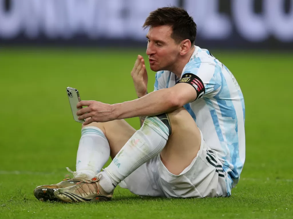 Messi video call keluarganya di lapangan usai juara Copa America 2021. (photo/REUTERS/RICARDO MORAES)