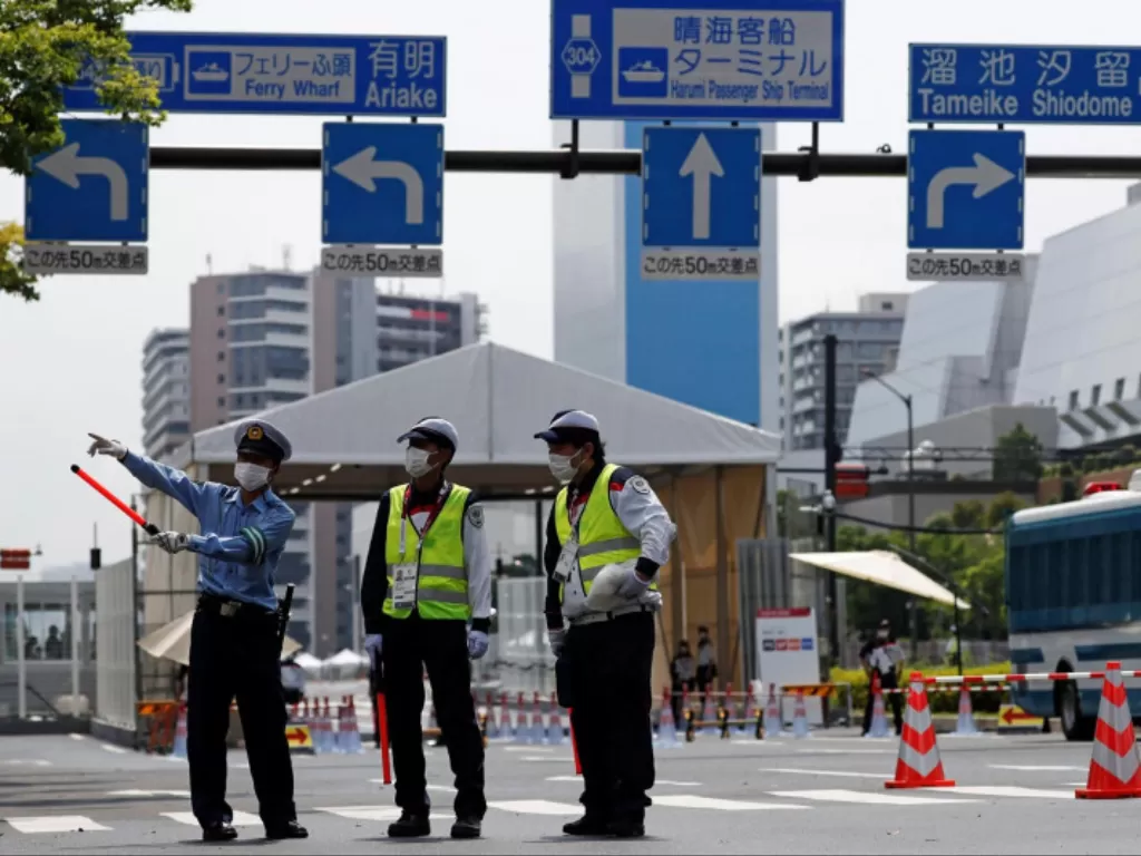 Petugas kepolisian dan personel keamanan berjaga di pintu masuk Desa Atlet menjelang Olimpiade Tokyo 2020 yang telah ditunda hingga 2021 karena COVID-19, di Tokyo, Jepang, Selasa (13/7/2021). (REUTERS/Issei Kato)