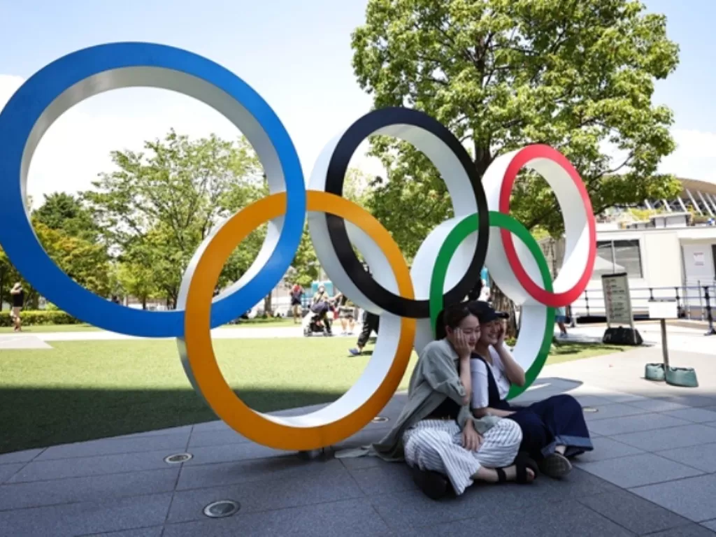 Dua orang wanita sedang berfoto di depan logo Olimpiade di Tokyo (REUTERS/Hannah Mckay)