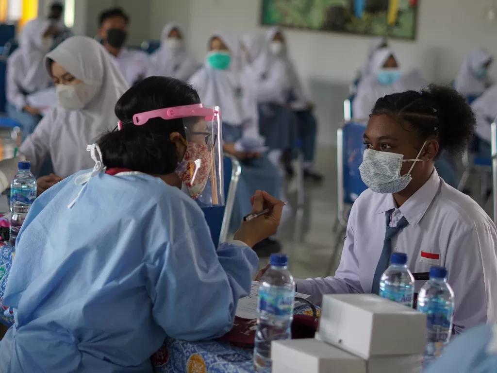 Petugas kesehatan memeriksa kesehatan seorang pelajar saat vaksinasi COVID-19 (ANTARA/Harviyan Perdana Putra)