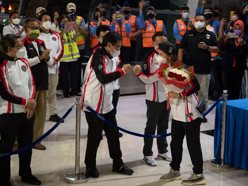 Pebulutangkis ganda putri peraih medali emas Olimpiade Tokyo 2020 Greysia Polii (kanan) melakukan tos dengan Ketua Umum PBSI Agung Firman Sampurna (tengah). (ANTARA/Aditya Pradana Putra)