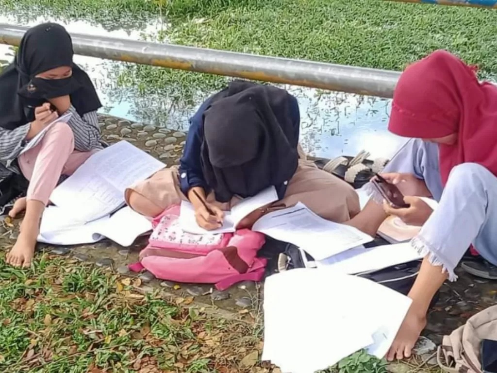 Beberapa siswa  belajar di tepi Sungai Kinal demi bisa mendapatkan sinyal internet (ANTARA/Helti Marini Sipayung)