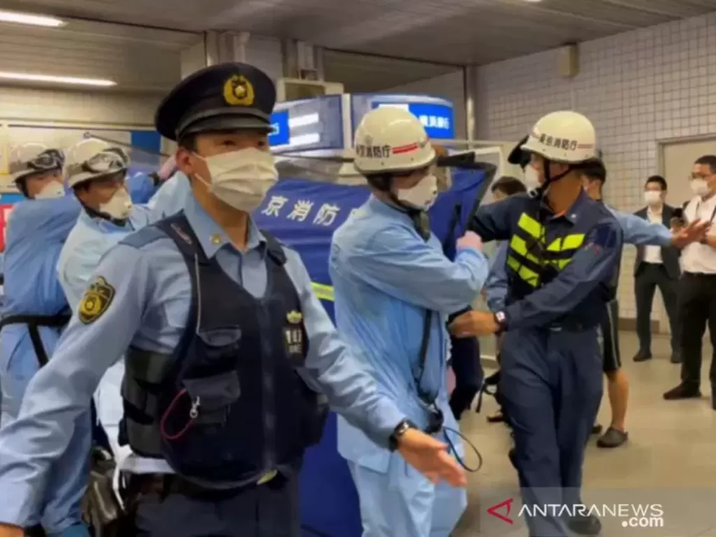 Polisi mengawal petugas penyelamat yang membawa seseorang melalui stasiun kereta api setelah serangan pisau di kereta api di Tokyo, Jepang 6 Agustus 2021 dalam gambar diam yang diambil dari video yang diperoleh REUTERS. (photo/REUTERS/HO)
