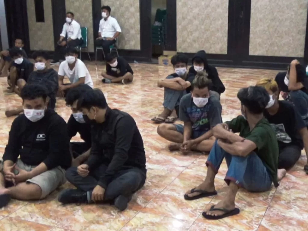 Sejumlah pemuda terduga pelaku yang menghadiri laga duel tarung bebas ilegal bersiap menjalani tes urine dan COVID-19 usai ditangkap aparat kepolisian, di aula kantor Polrestabes Makassar, Sulawesi Selatan, Senin (9/8/2021). (photo/ANTARA/HO)