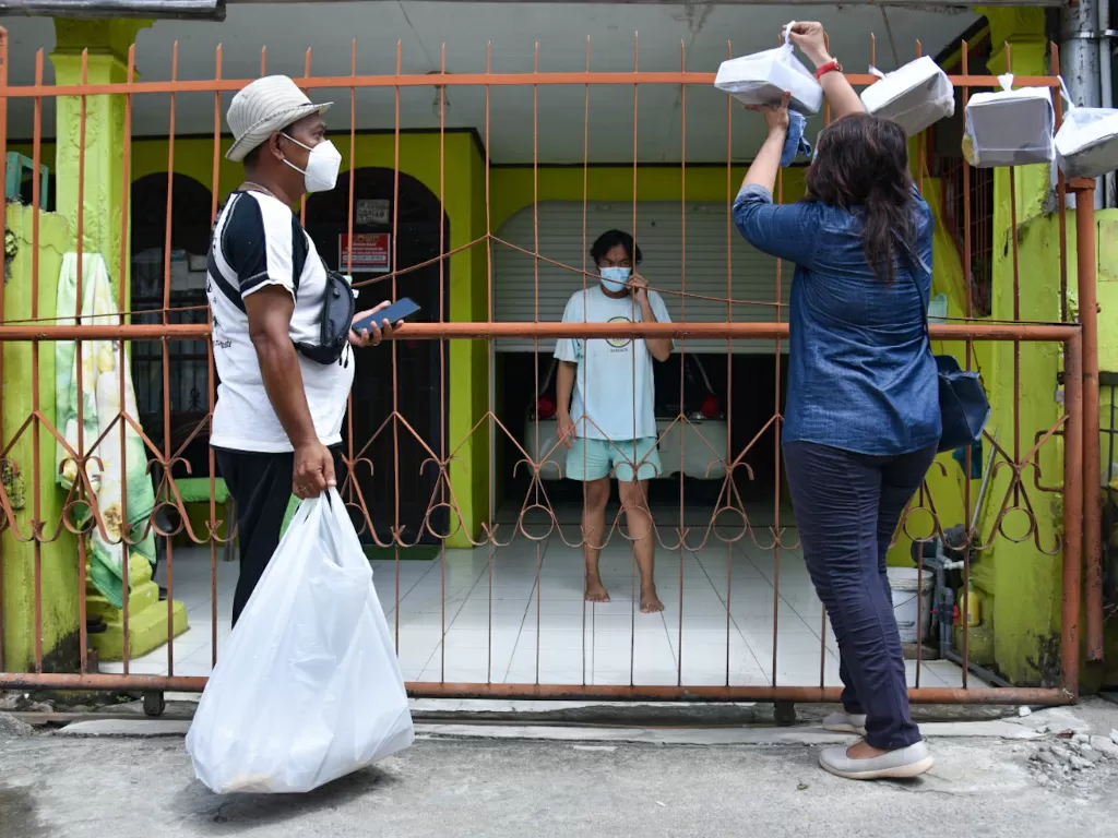 Ilustrasi - Relawan bersama Kepala Lingkungan menggantung bantuan makanan di pagar warga yang menjalani isolasi mandiri (isoman) di Medan Tuntungan, Medan, Sumatera Utara, Rabu (4/8/2021). (ANTARA/Fransisco Carolio)