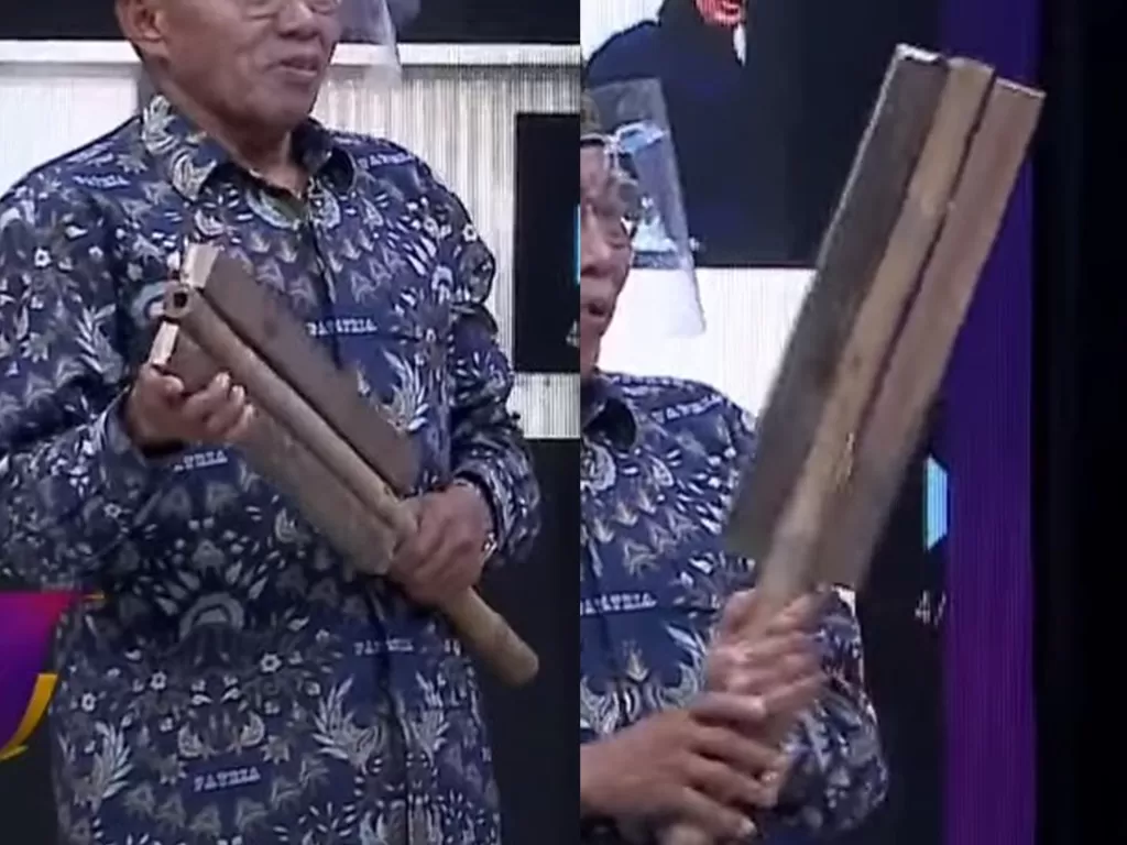 Ayah Apriyani Rahayu, Amiruddin Pora memperlihatkan raket kayu yang menjadi saksi bisu perjalanan karir bulu tangkis sang putri. (Tangkapan layar/YouTube)