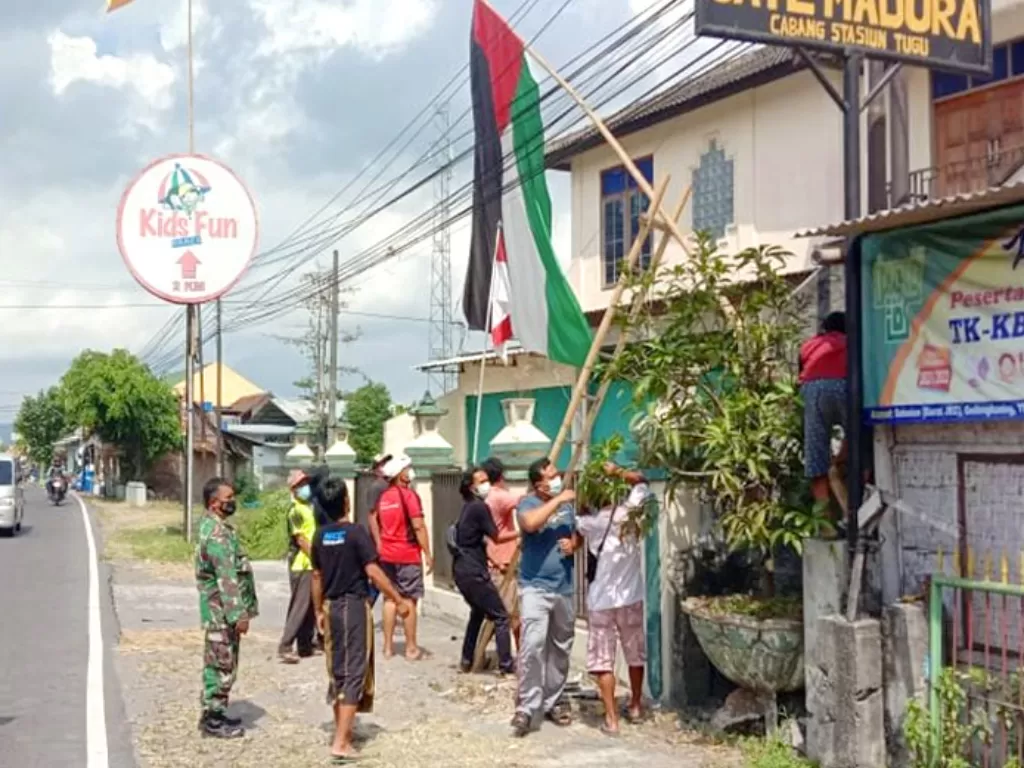 Warga bersama petugas menurunkan bendera Palestina yang terpasang di rumah warga. (Twitter)