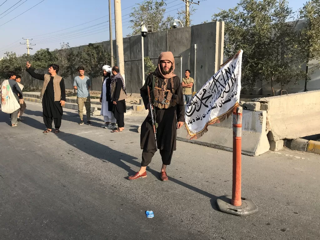 Seorang anggota Taliban berdiri di luar Kementerian Dalam Negeri di Kabul. (REUTERS/Stringer)