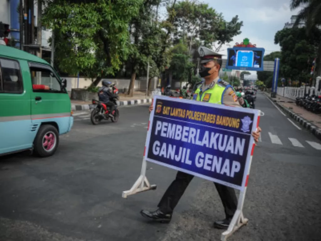 Petugas Kepolisian membawa papan informasi saat uji coba pemberlakuan ganjil genap di Jalan Asia-Afrika, Bandung, Jawa Barat, Jumat (13/8/2021). (ANTARA FOTO/Raisan Al Farisi)