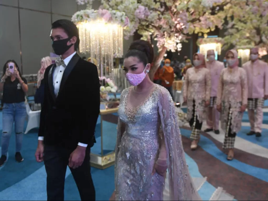 Pasangan pengantin mengenakan masker dalam simulasi pernikahan di era new normal di Jakarta, Kamis (9/7/2020). (ANTARA FOTO/Akbar Nugroho Gumay)