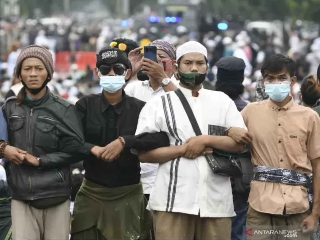 Massa pendukung Rizieq Shihab bergandengan tangan membentuk barikade di kawasan I Gusti Ngurah Rai saat akan menuju Pengadilan Negeri (PN) Jakarta Timur, Kamis (24/6/2021). (Antara//M Risyal Hidayat)
