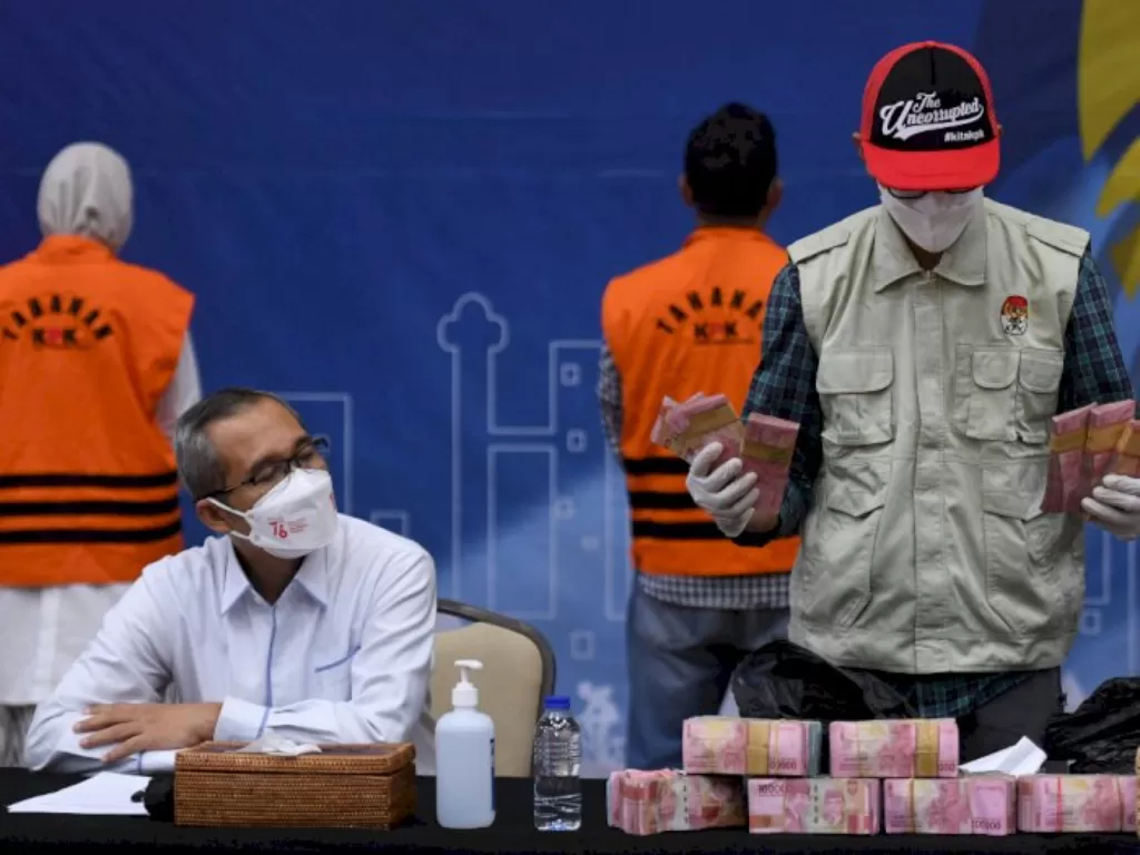 Wakil Ketua KPK Alexander Marwata (duduk kiri) menyaksikan penyidik KPK menunjukkan barang bukti hasil OTT Bupati Purbolinggo di gedung KPK, Jakarta, Selasa (31/8/2021) dini hari. (Foto: ANTARA/Hafidz Mubarak)