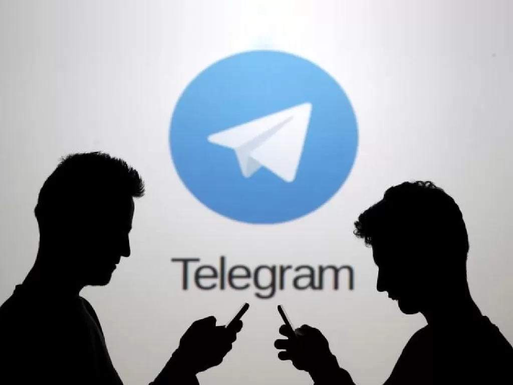 Ilustrasi dua orang yang berdiri di depan logo Telegram (photo/REUTERS/Dado Ruvic)