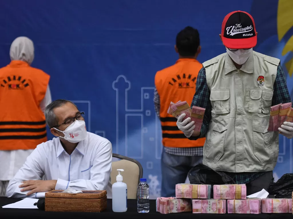 Wakil Ketua KPK Alexander Marwata (duduk kiri) menyaksikan penyidik KPK menunjukkan barang bukti hasil OTT Bupati Purbolinggo di gedung KPK, Jakarta, Selasa (31/8/2021) dini hari. (Foto: ANTARA/Hafidz Mubarak)