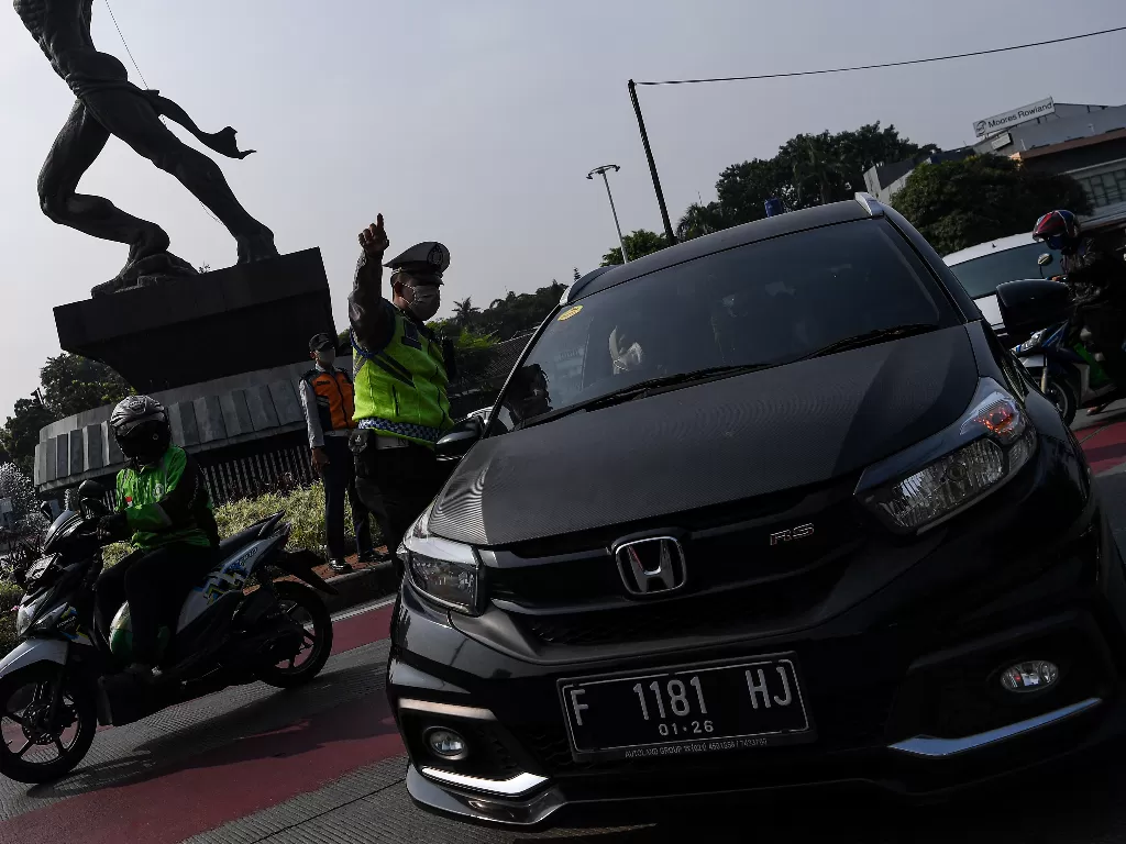 Polisi mengatur lalu lintas kendaraan di pos penerapan ganjil genap di kawasan Bundaran Senayan, Jakarta. (ANTARA FOTO/Sigid Kurniawan).