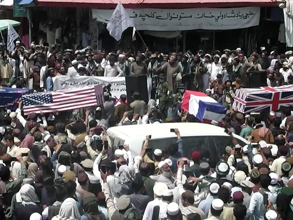 Massa pendukung Taliban pada Selasa (31/8) mengarak peti-peti mati yang dibungkus dengan bendera Amerika Serikat (AS) serta Pakta Pertahanan Atlantik Utara (NATO) di kota timur, Khost. (REUTERS)
